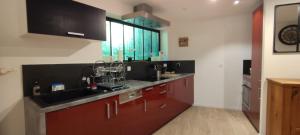 a kitchen with red cabinets and a sink and a window at O'Cœur de la Roche - Jacuzzi et Hammam privatif in Saint-Blaise-la-Roche