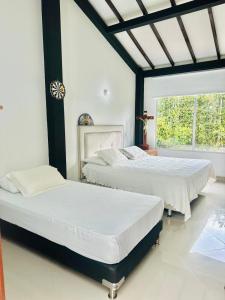 Dos camas en un dormitorio con ventana. en Lujosa casa cerca al aeropuerto, en Medellín