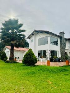 una casa blanca con una palmera en el patio en Lujosa casa cerca al aeropuerto, en Medellín
