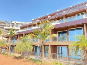 an apartment building with palm trees in front of it at Panorama Seascape in Harnai
