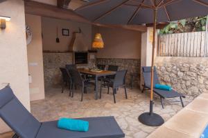 a patio with a table and chairs and an umbrella at Stadthaus - Alica 8 - Pool, Barbecue, Garten, Terrassen und im Winter Zentralheizung und Kamin, hochwertig saniert in Pollença
