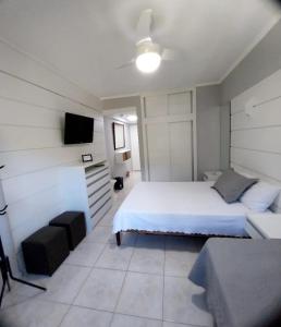 a bedroom with a white bed and a television at Cavalinho Branco 215 in Águas de Lindóia