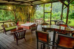 a porch with tables and chairs and a couch at Cabaña Los Tucanes in Fortuna +25 photos