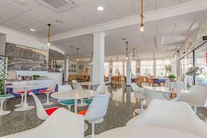 un restaurante con mesas y sillas blancas, mesas y ventanas en Hotel Altaia, en Altea