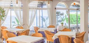 Un restaurante con mesas y sillas blancas y ventanas. en Hotel Altaia, en Altea