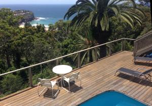 a deck with chairs and a table and the ocean at Avalon Horizons in Bilgola