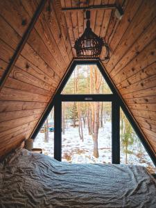 a bedroom with a large window in a cabin at Leśna Chatka in Wola Polska