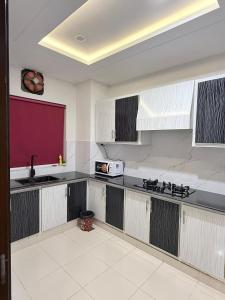 a kitchen with white and black cabinets and a microwave at The Loft Life in Islamabad