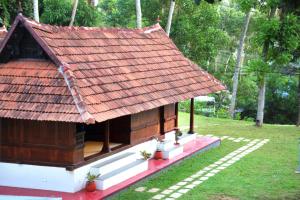 a small house with an orange roof in a field at Poovar Heritage Homes in Pūvār