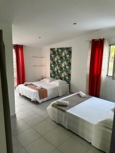 two beds in a bedroom with red curtains at Maison La Surprise in Saint-Leu +10 photos
