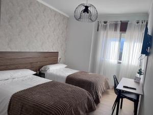 ein Schlafzimmer mit zwei Betten, einem Schreibtisch und einem Fenster in der Unterkunft Dimar in Quiroga