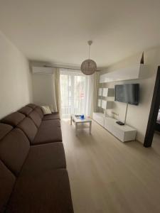 a living room with a brown couch and a tv at Apartmán Hollého in Žilina