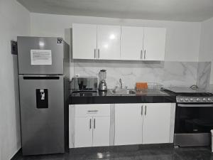 a kitchen with white cabinets and a stainless steel refrigerator at Casa Cachi in Mexico City
