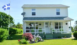 a white house with a flag in the yard at Gite Nycole in Perce