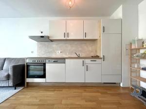 una cucina con armadi bianchi e un divano grigio di Wohnung mit Garten in 1230 Wien a Vienna