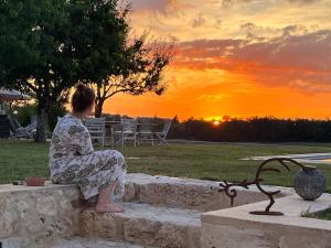 a woman sitting on a stone bench watching the sunset at B&B La Mirande de Saint-Clar in Saint-Clar