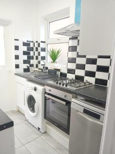 a kitchen with a stove and a washing machine at Time Space Bliss in Dagenham Dock