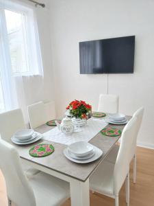 a dining room table with white chairs and a television at Time Space Bliss in Dagenham Dock