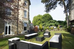 a garden with benches and tables in front of a building at Applewood Hotel in Bournemouth +19 photos