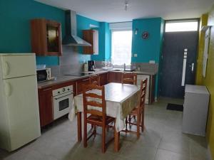a kitchen with a table and chairs and a white refrigerator at Logement dans la campagne nérisienne in Néris-les-Bains