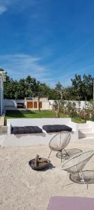 a patio with two beds and a chair in the sand at Villa Korta Regina in Ston +25 photos