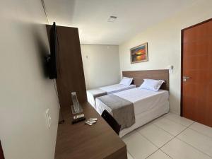 a hotel room with two beds and a television at Pousada Sousa&Araújo in Juazeiro do Norte