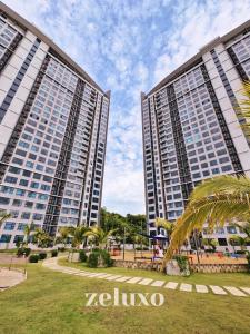 two tall buildings with palm trees in a park at Zeluxo #JQ02 Jesselton Quay Tower 2 Level 10-2 BR 1 Bath, Seaview in Kota Kinabalu