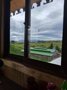 a window with a view of a barn and a field at El Al Patagonia in Puerto Natales