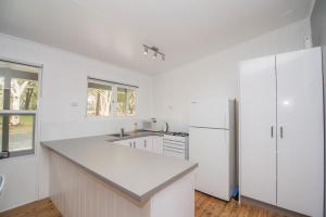 a kitchen with white cabinets and a white refrigerator at Lakeside Cabins & Holiday Village in Sussex inlet