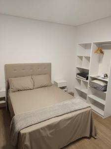 a white bedroom with a bed and shelves at Apto sacada vista mar navegantes in Navegantes