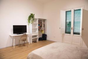 a white bedroom with a desk and a television at Spalti 33 in Trapani