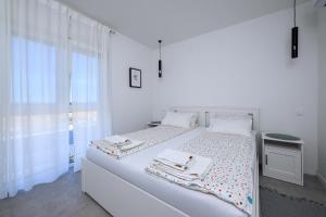 a white bedroom with a large white bed and a window at Roris House in Povljana
