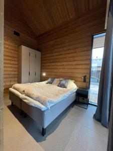 Un dormitorio con una cama y una pared de madera. en Lakeside Chalet Vinkka, en Kilpisjärvi