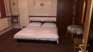 a bedroom with a bed with two pillows and a table at Zeke Szálláshely in Vác