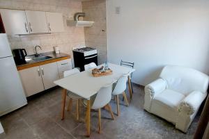 eine Küche mit einem weißen Tisch, Stühlen und einem Herd in der Unterkunft La Fueguina Departamento 4 en Gobernador Gregores in Gobernador Gregores + 3 Fotos