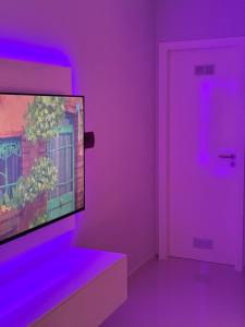 a room with a purple room with a tv and a door at Alojamento Ribeirinha in Mindelo