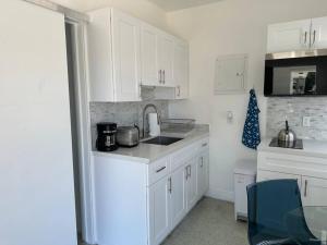 a kitchen with white cabinets and a sink at Villa Clara Blue-Little Havana in Miami
