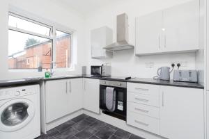 a kitchen with white cabinets and a washer and dryer at HIGH STREET APARTMENT, SLEEPS 6 GUESTs! in Bedworth