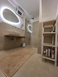 ein Badezimmer mit Waschbecken, Spiegel und Dusche in der Unterkunft Trullo il Gelso with Private Salt Water Infinity Pool and Jacuzzi inside in San Michele Salentino