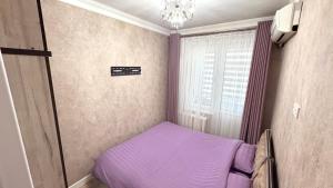 - une petite chambre avec un lit violet et une fenêtre dans l'établissement Abay street- Tashkent city center, à Tachkent