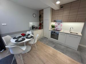 een keuken met een tafel en witte stoelen in een kamer bij Rewal Cliff Morska 1 in Rewal