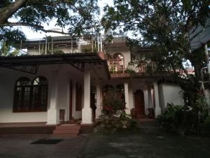 a white house with a tree in front of it at DeBee home stay in Kurunegala