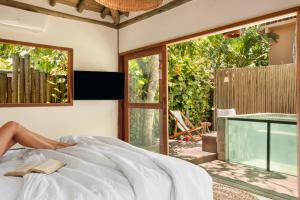 a woman laying on a bed in a bedroom with a window at Villa Rio Caraiva in Caraíva