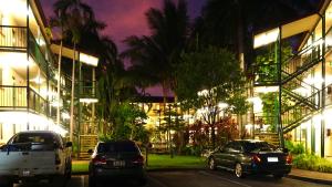 dos autos estacionados frente a un edificio por la noche en Alatai Holiday Apartments, en Darwin