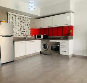 a kitchen with white cabinets and a washer and dryer at Appart Cosy Résidence Perla in Saïdia