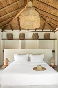 a bedroom with a white bed with a hat on it at Villa Rio Caraiva in Caraíva +90 photos