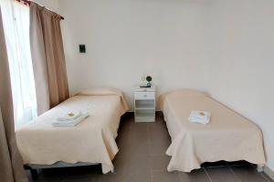 zwei Einzelbetten in einem Zimmer mit Fenster in der Unterkunft La Fueguina Departamento 2 en Gobernador Gregores in Gobernador Gregores
