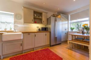a kitchen with a refrigerator and a red rug at Shrimpers Cottage in Lytham St Annes