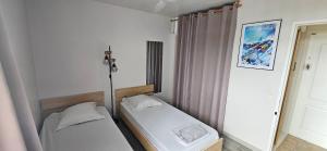 two beds in a small room with a window at Le 5ème étage du bonheur in Pointe-à-Pitre