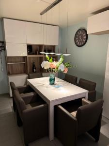 a dining room table with chairs and a vase of flowers at Vakantiewoning dichtbij zee in Bredene